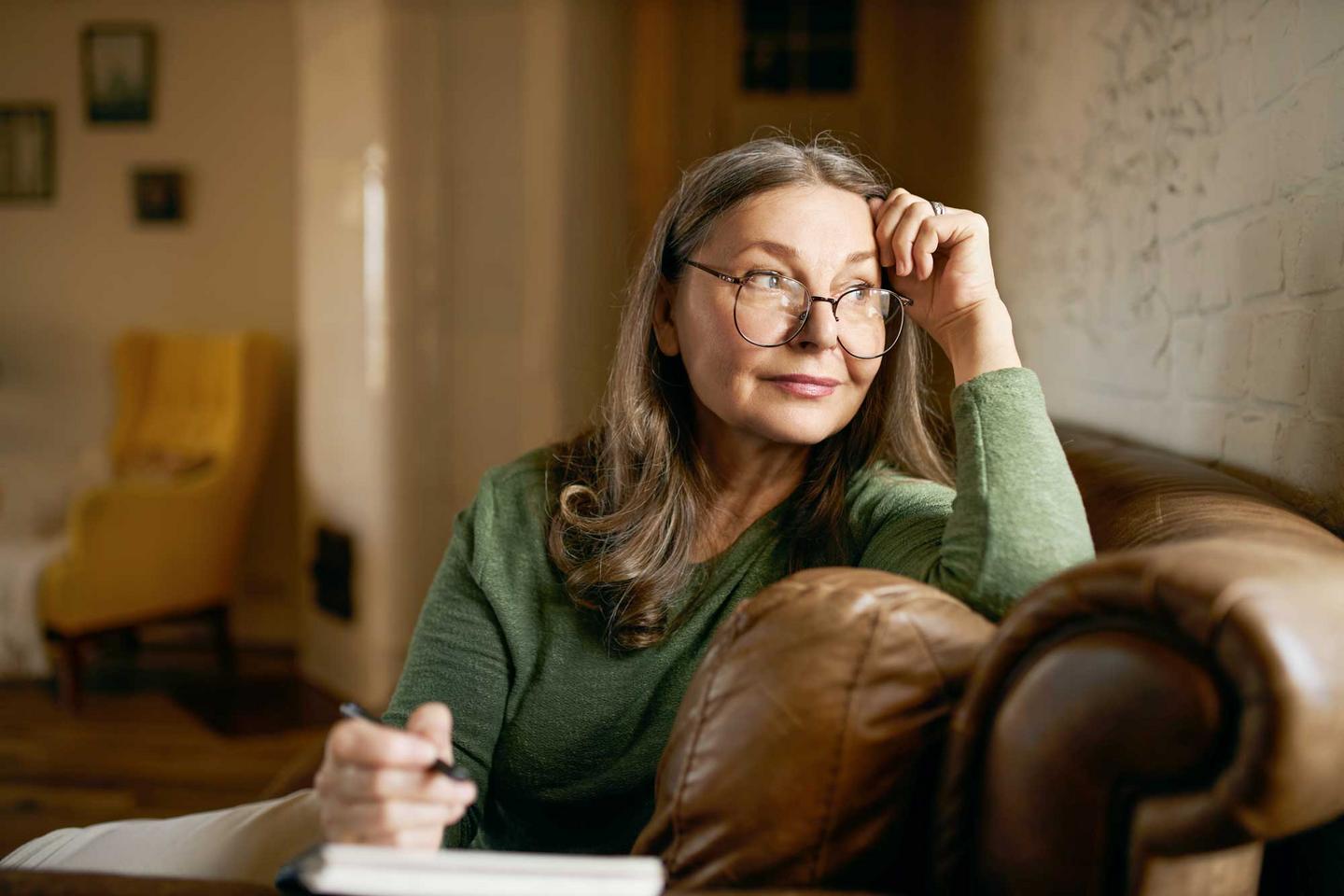 Frau sitzt auf dem Sofa mit Notizblock und Stift