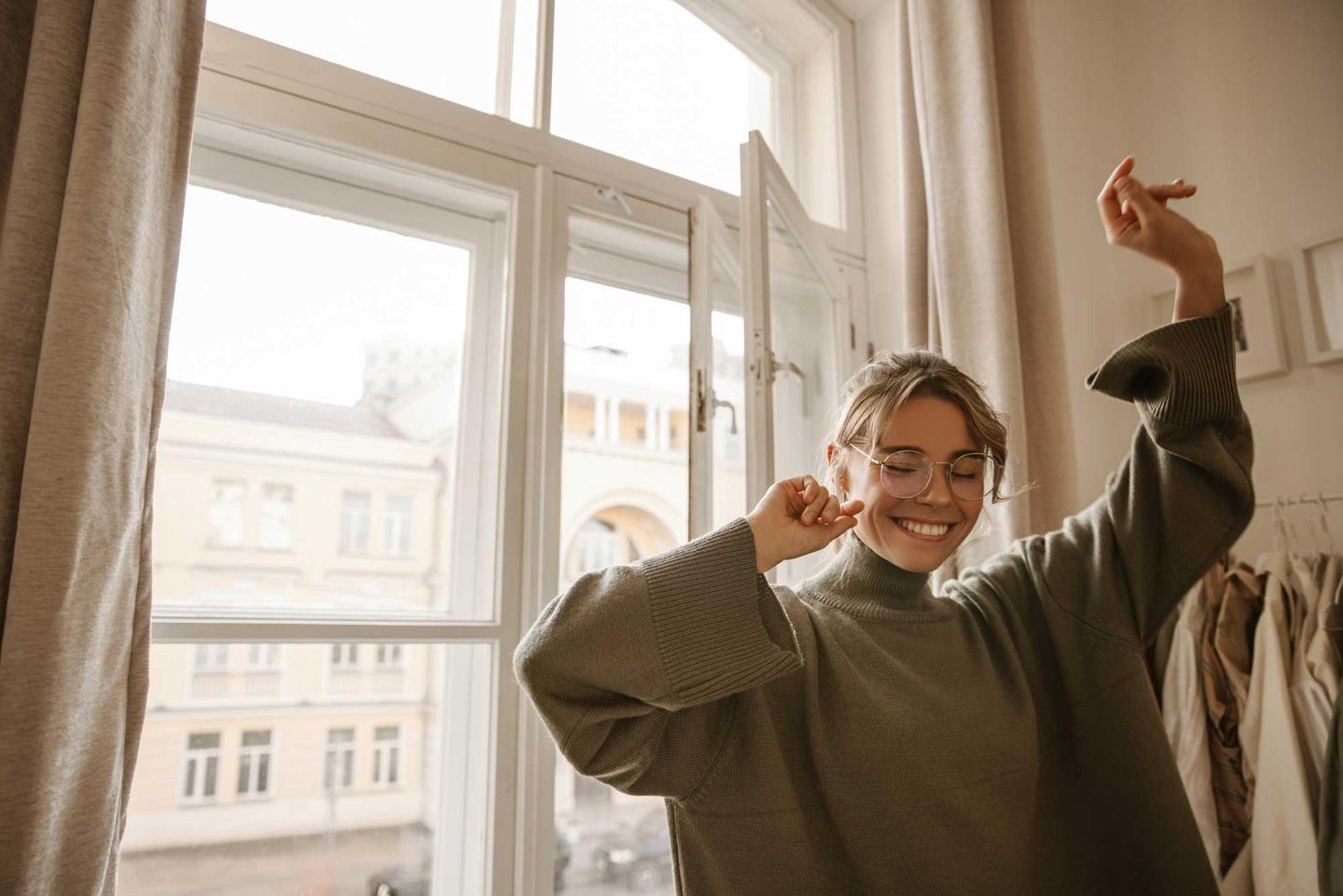 Junge Frau tanzt fröhlich durch die Wohnung