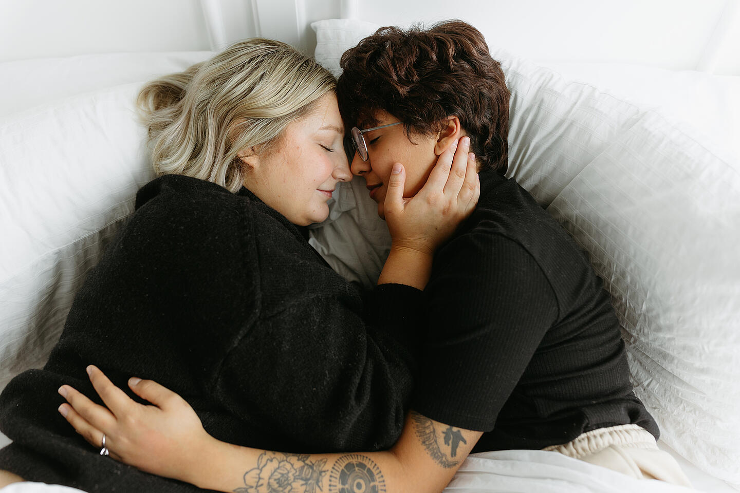 Zwei Frauen liegen im Bett und umarmen sich