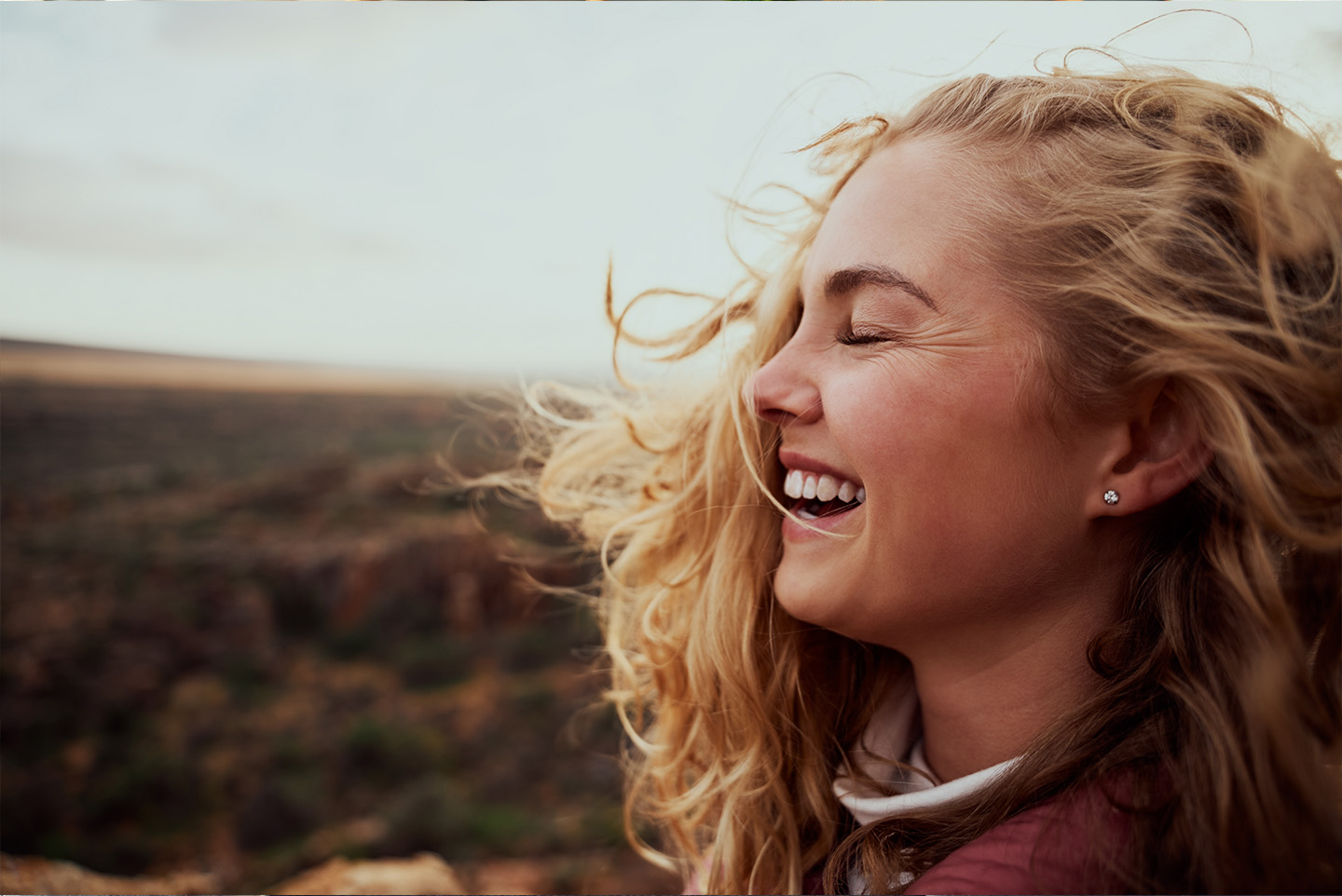 Bildnachweis: © stock.adobe.com / StratfordProductions Junge Frau hält lachend ihr Gesicht in den Wind